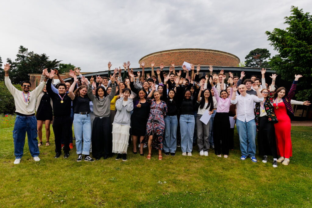 Група людей радісно піднімає руки на галявині.