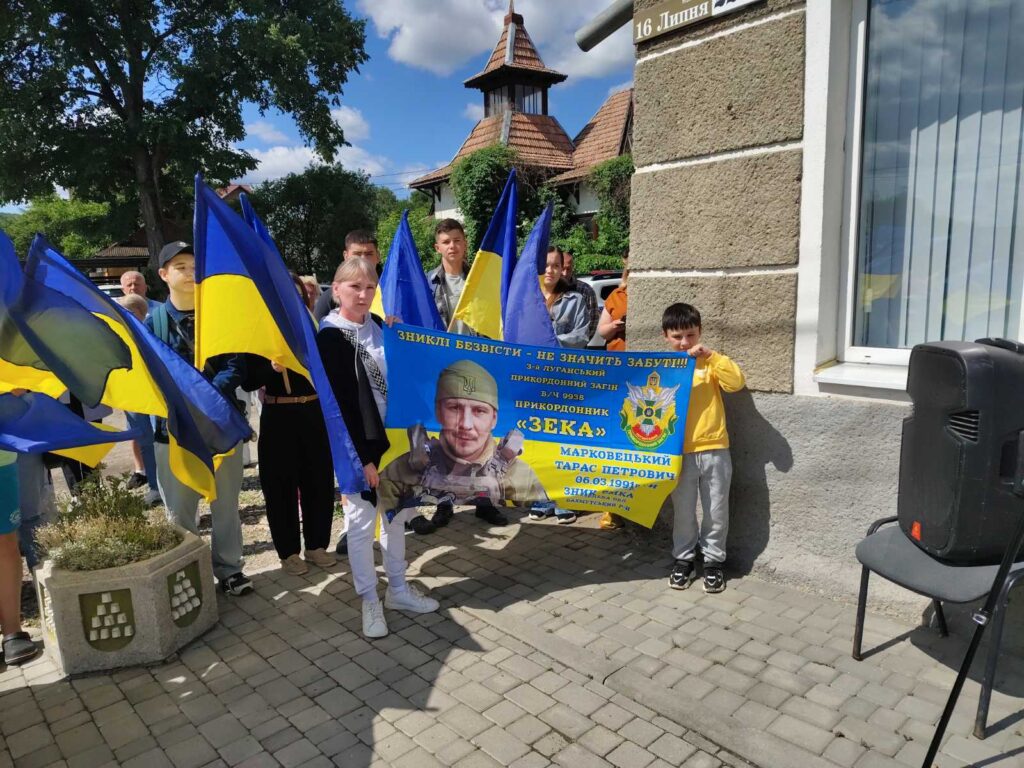 Люди з українськими прапорами на вулиці.