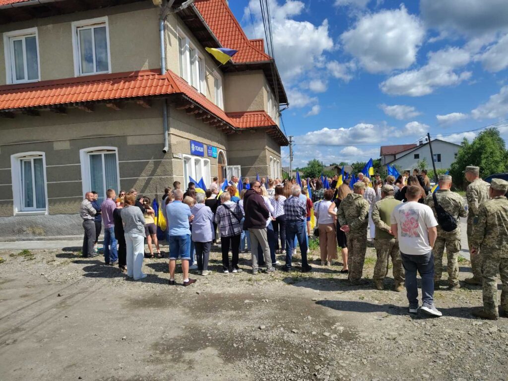 Зібрання людей із прапорами біля будівлі.