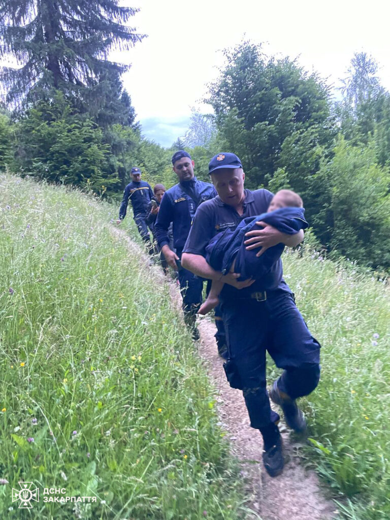 Рятувальники несуть дитину лісовою дорогою.