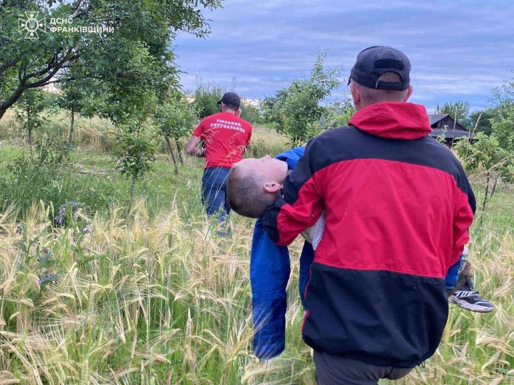 Рятівник несе людину на полі.