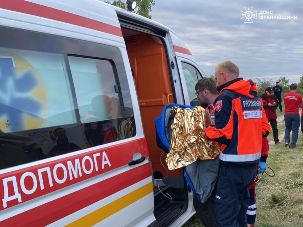 Рятувальники допомагають постраждалому біля швидкої допомоги.