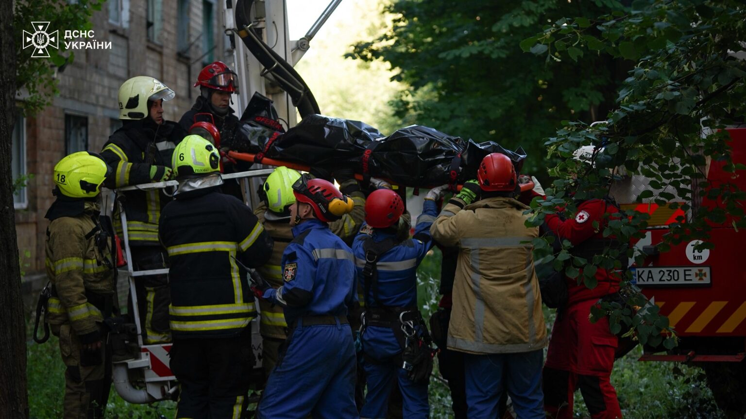 Рятувальники працюють біля будівлі в зеленій зоні.