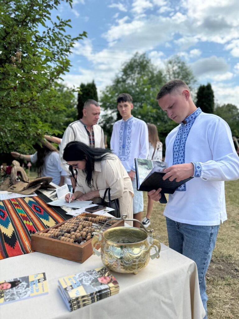 Люди у вишиванках пишуть і читають на вулиці.