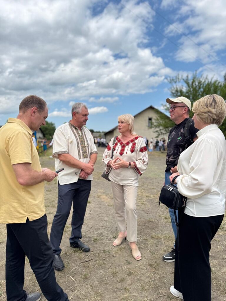 Люди обговорюють на відкритому повітрі під хмарним небом.