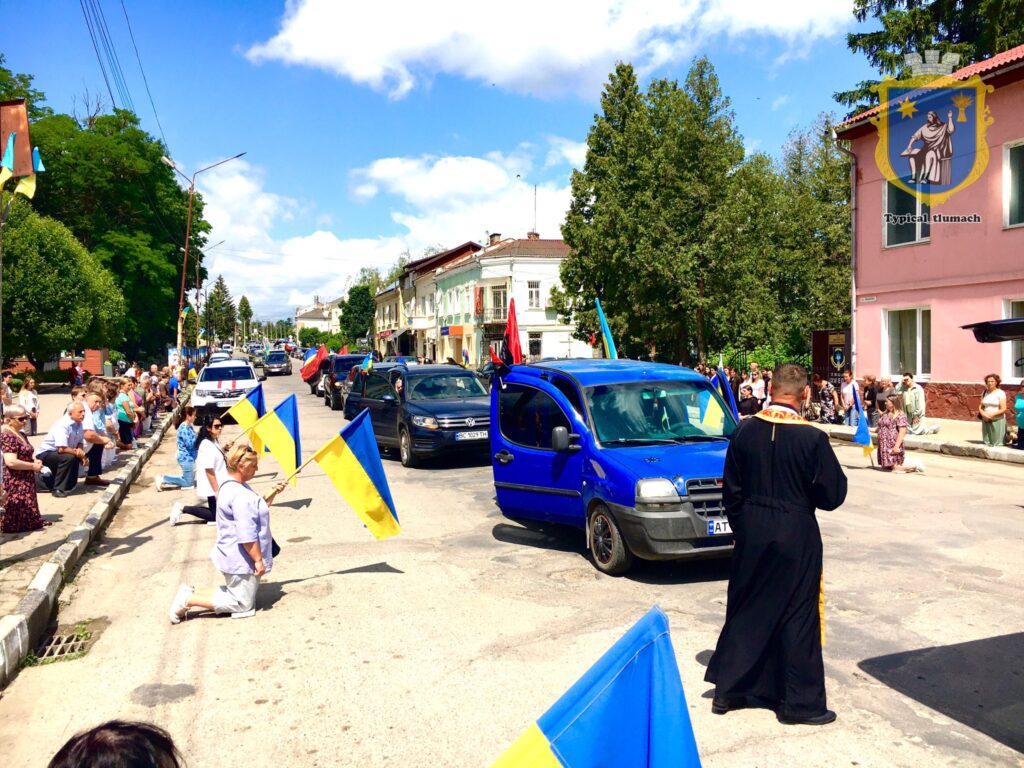 Люди з прапорами клякають на дорозі під час події.