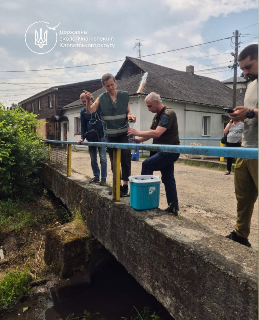 Інспектори беруть зразки води з річки.