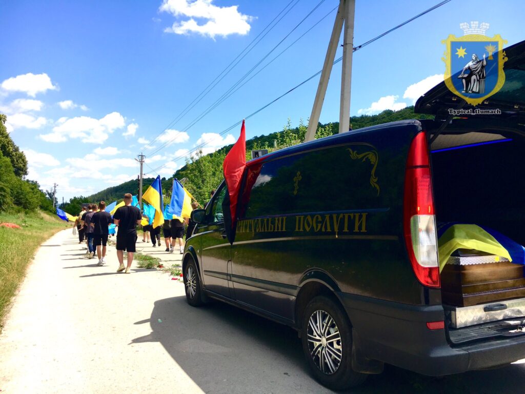 Процесія з українськими прапорами та ритуальним авто