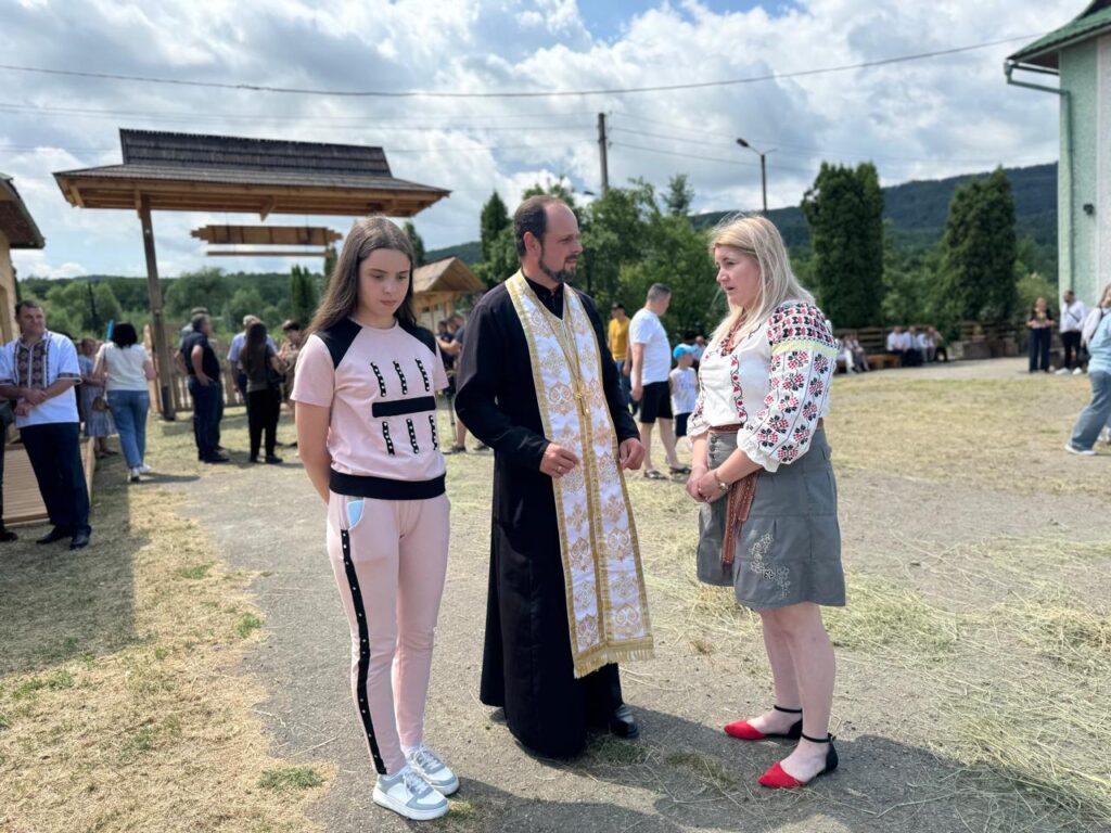 Троє людей на традиційному святі під відкритим небом.