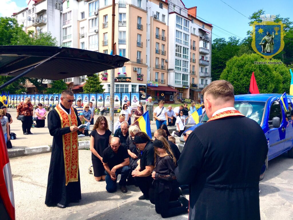 Священик і люди моляться на вулиці міста.