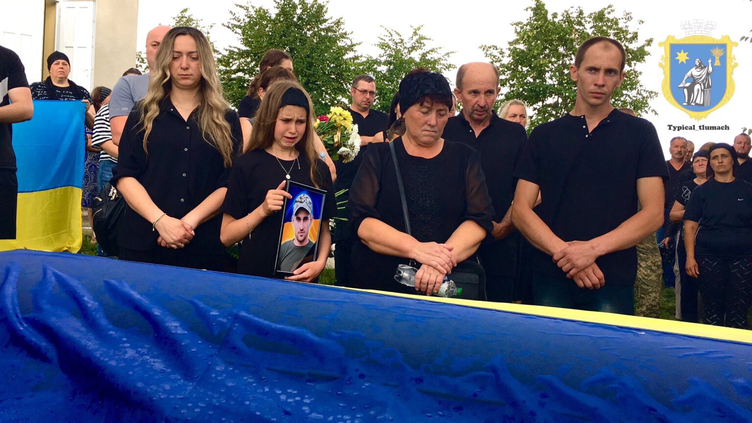 Люди на похороні з прапором України.