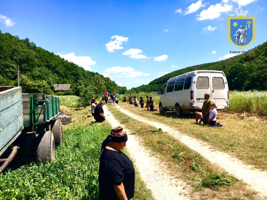 Люди на колінах обабіч дороги біля мікроавтобуса.