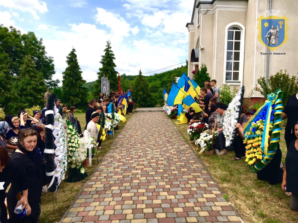 Урочистий захід з прапорами України біля церкви.