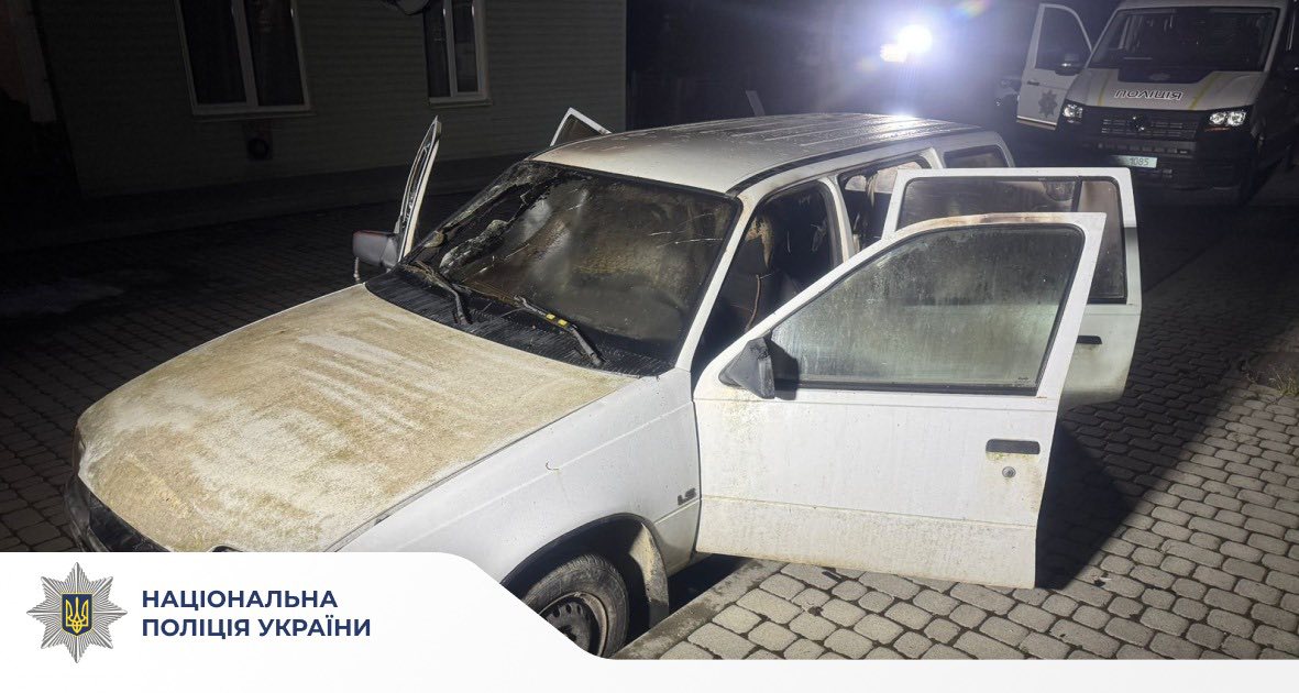 Відкрита біла машина біля поліцейського фургона.