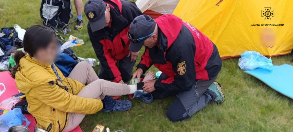 Рятувальники надають допомогу жінці біля намету.