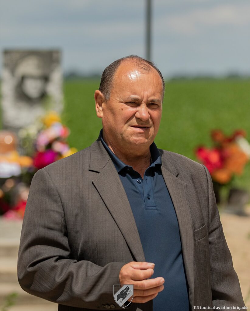 Чоловік у піджаку на вулиці, день сонячний.