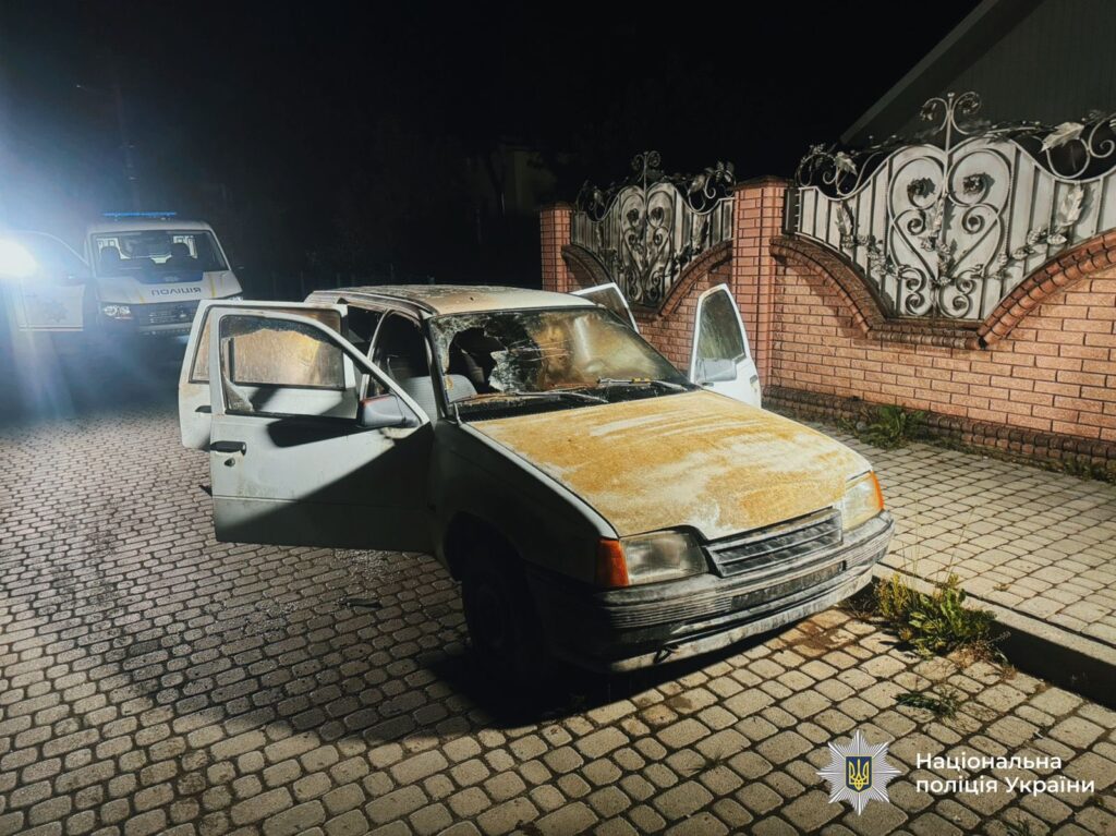 Пошкоджений автомобіль з поліцейською машиною на задньому плані.