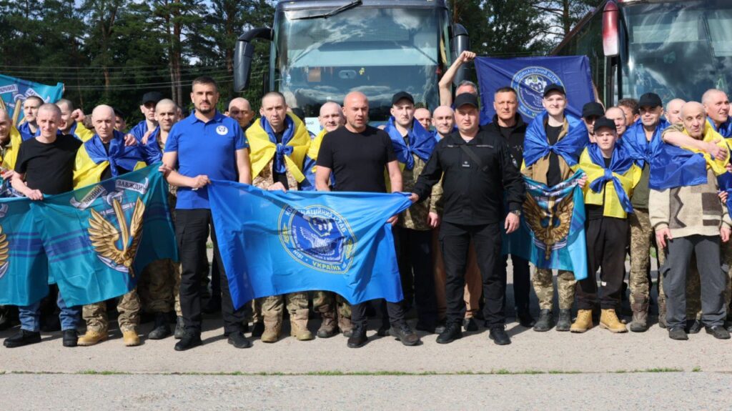 Група людей з українськими прапорами перед автобусами