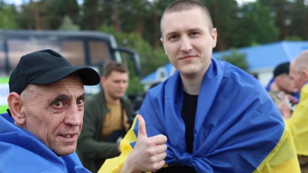 Двоє чоловіків з прапором України, один показує лайк.
