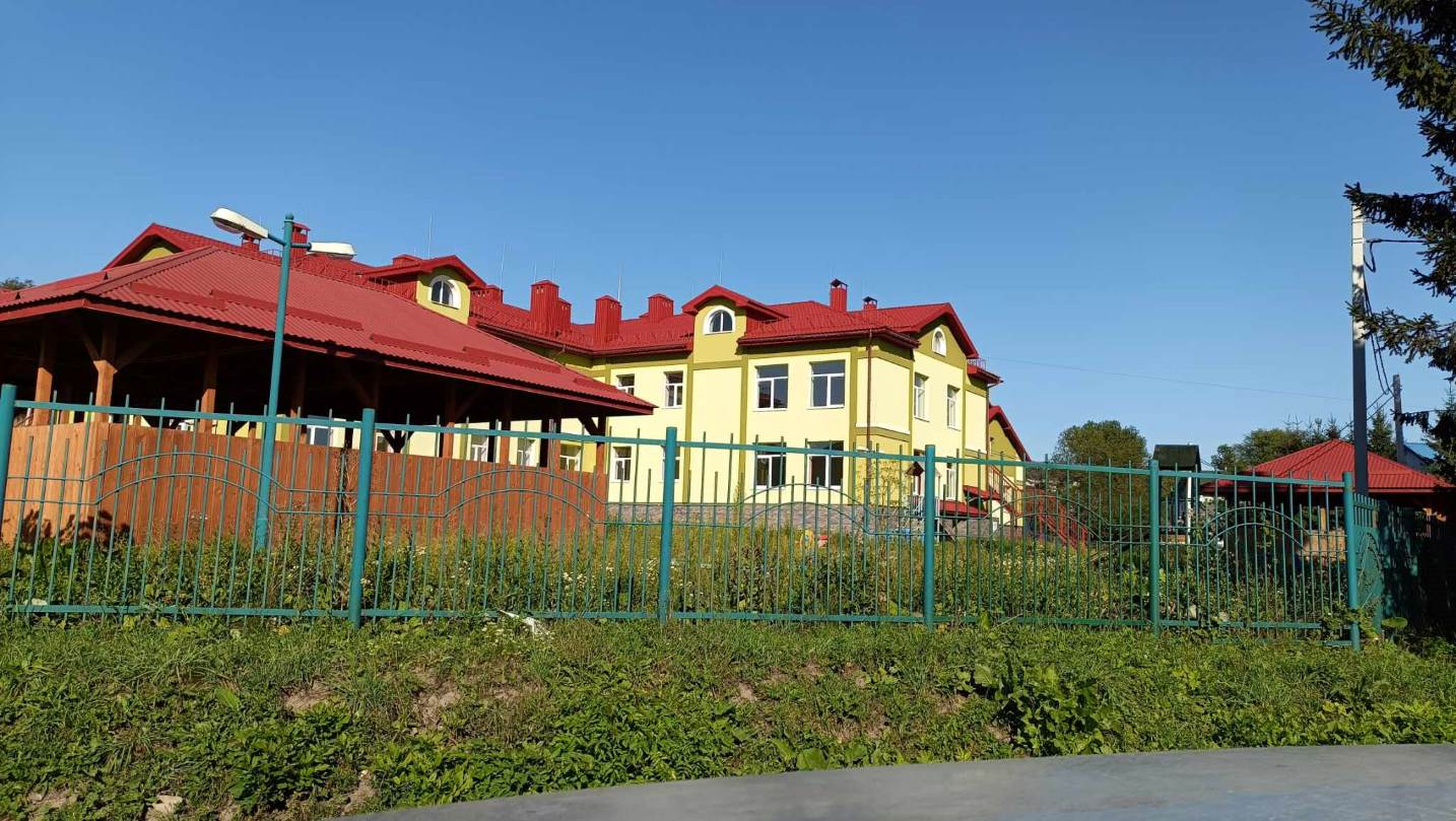 Жовтий будинок з червоним дахом і парканом