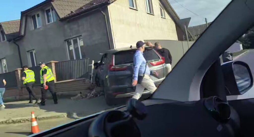 Аварія автомобіля біля будинку, люди на місці