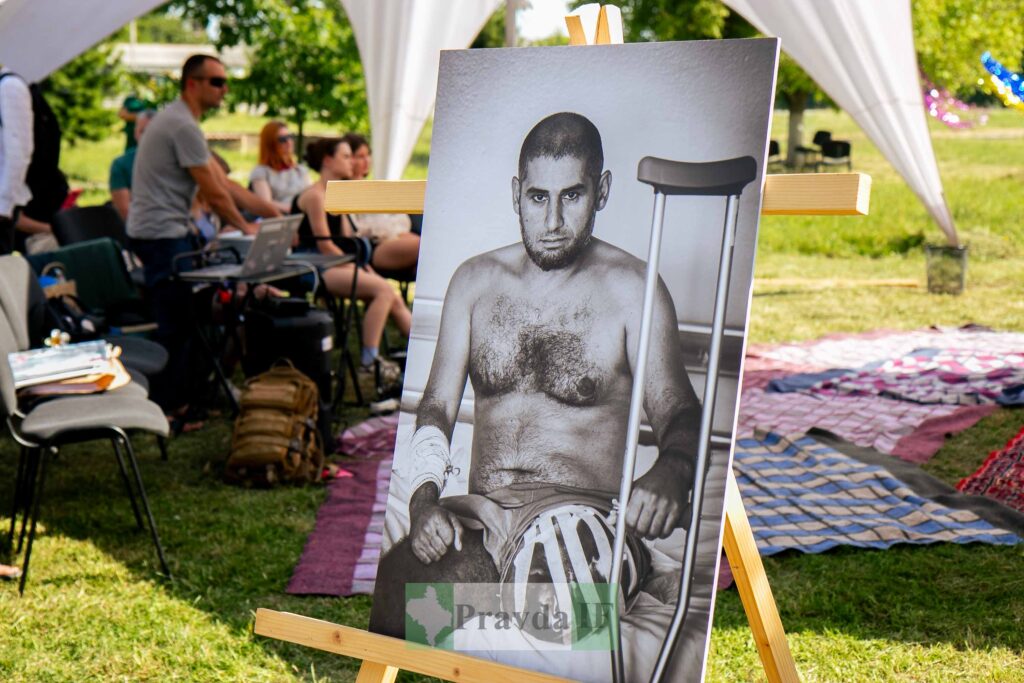 Фотопортрет чоловіка з милицею на виставці просто неба.