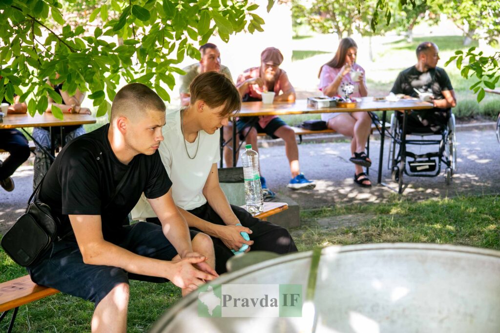 Люди відпочивають за столом в саду на природі.