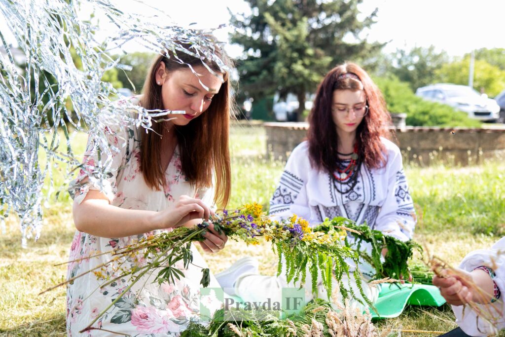 Жінки плетуть вінки з квітів на природі.