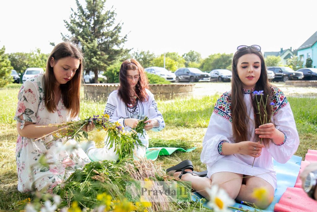 Жінки плетуть вінки з польових квітів.