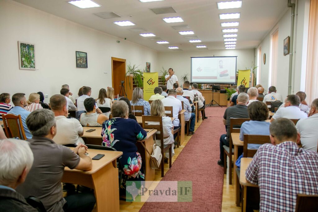 Конференція в залі з учасниками, проектор на екрані.