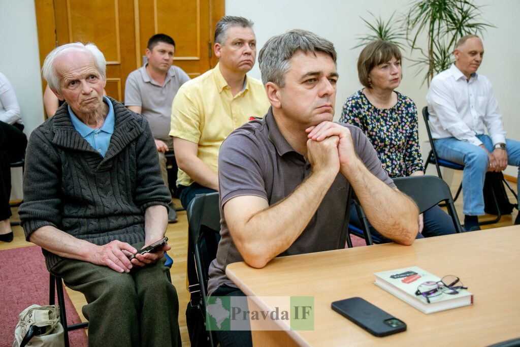 Люди сидять і слухають лекцію у приміщенні.