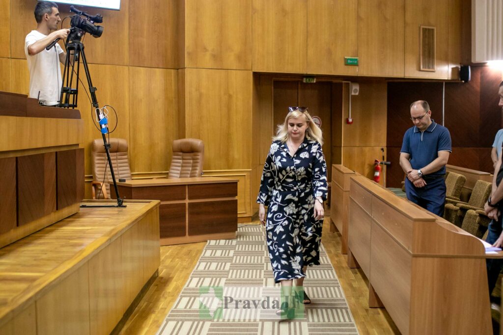 Жінка йде по залу засідань з камерами.