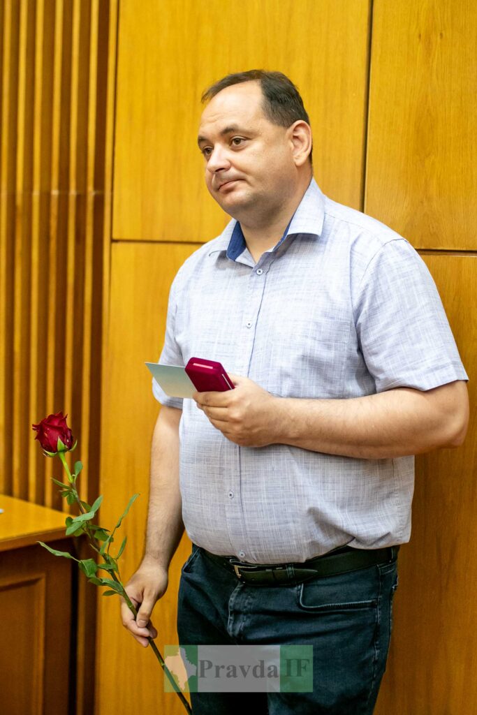 Чоловік з трояндою і коробкою на фоні дерев'яної стіни