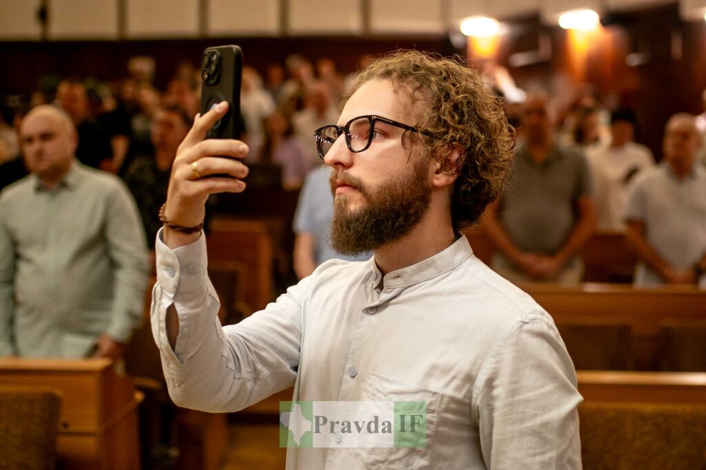 Чоловік фотографує на смартфон у залі засідання.