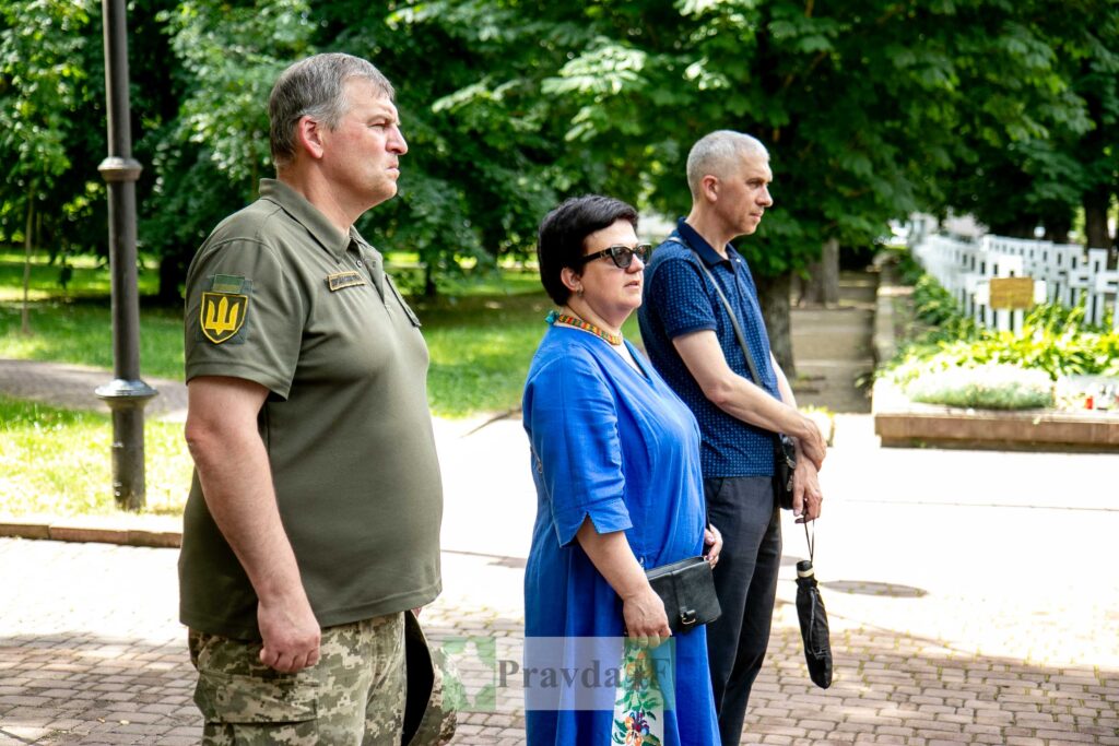 Троє людей стоять на вулиці в тіні дерев.