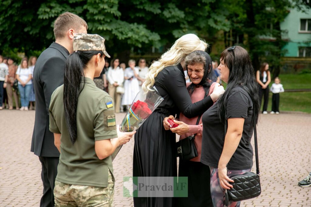Жінка обіймає літню жінку з квітами