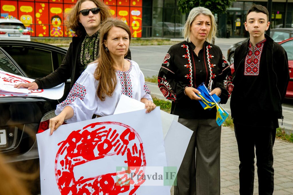 Люди у вишиванках тримають плакати на вулиці.