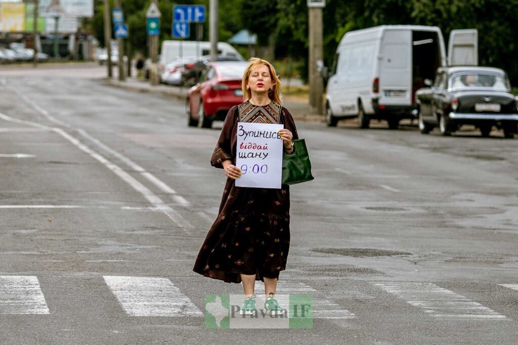 Жінка тримає знак на пішохідному переході