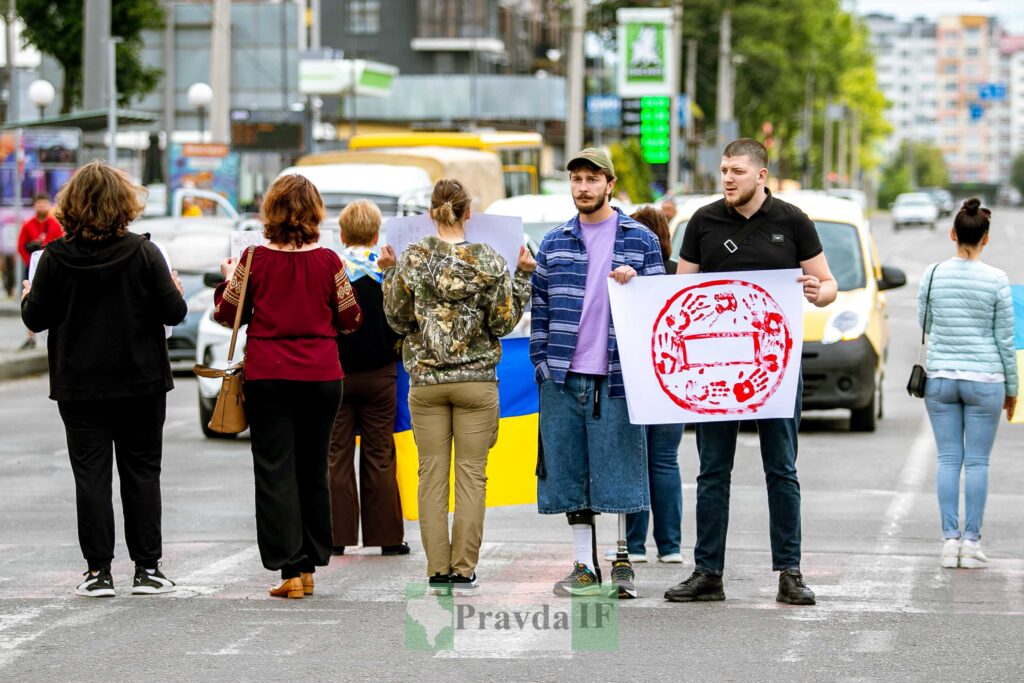 Люди протестують на вулиці з плакатами.