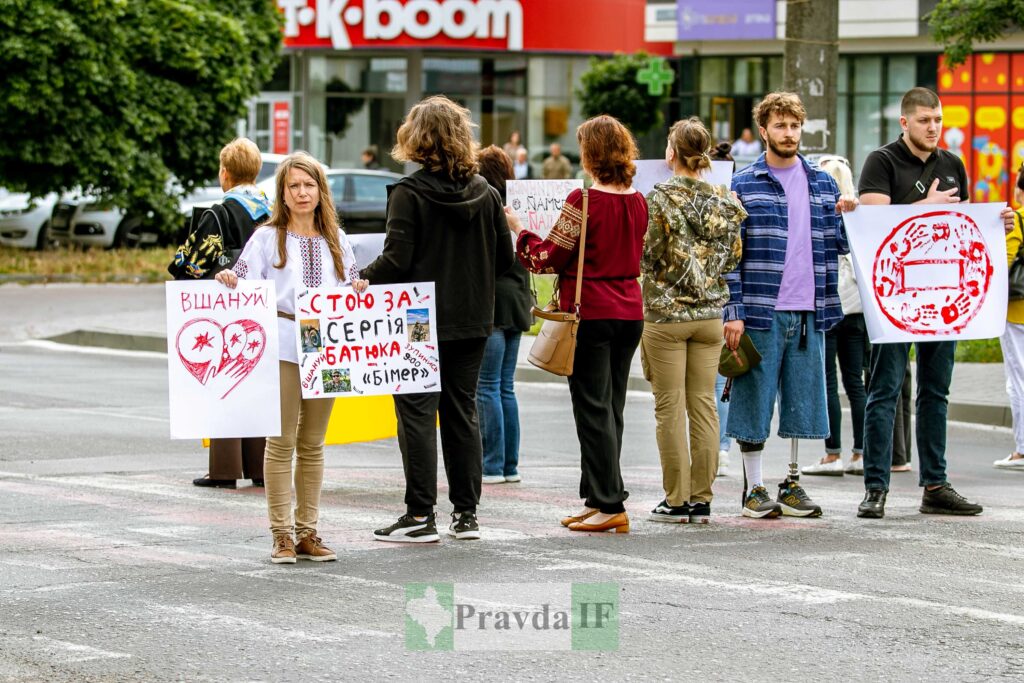 Люди на вулиці тримають плакати з протестом.