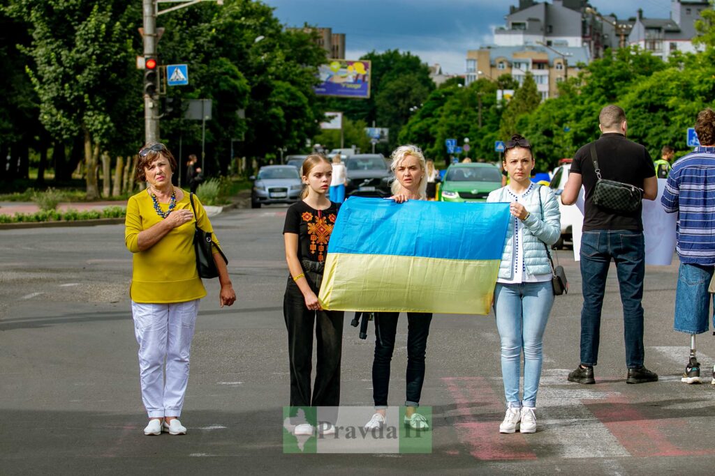 Люди тримають український прапор на вулиці.
