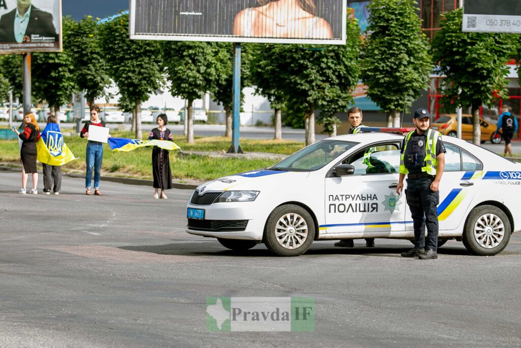 Поліцейська машина і люди з прапорами України