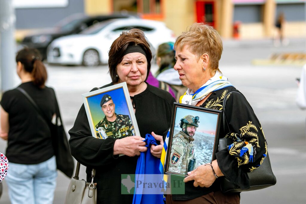 Жінки тримають портрети військових на вулиці.