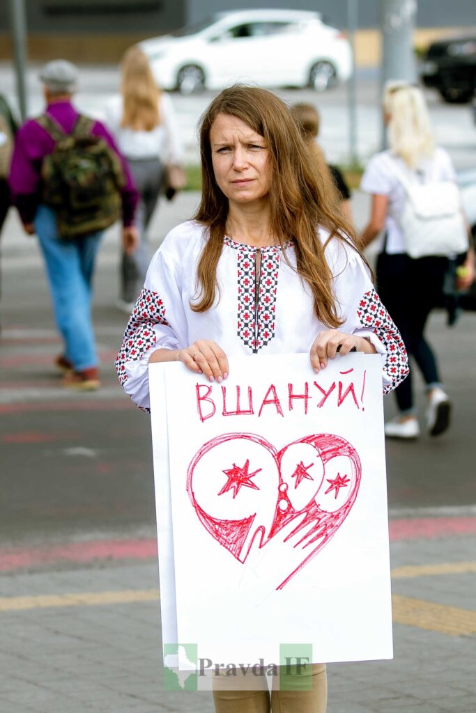 Жінка з плакатом на вулиці "Вшануй!