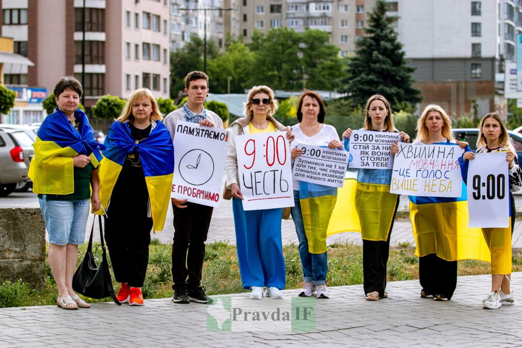 Люди тримають плакати біля будівель у місті.