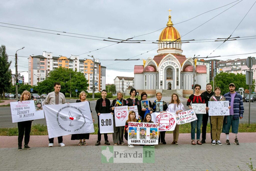Люди з плакатами перед церквою в Івано-Франківську.