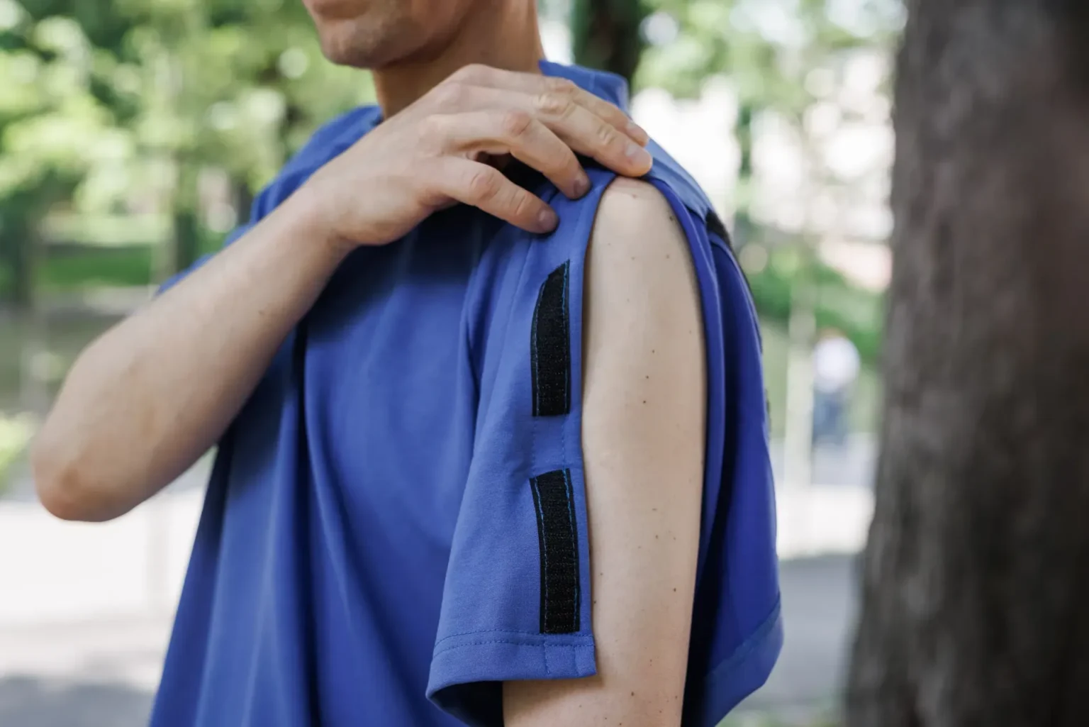 Людина в синій футболці із застібками на рукаві.