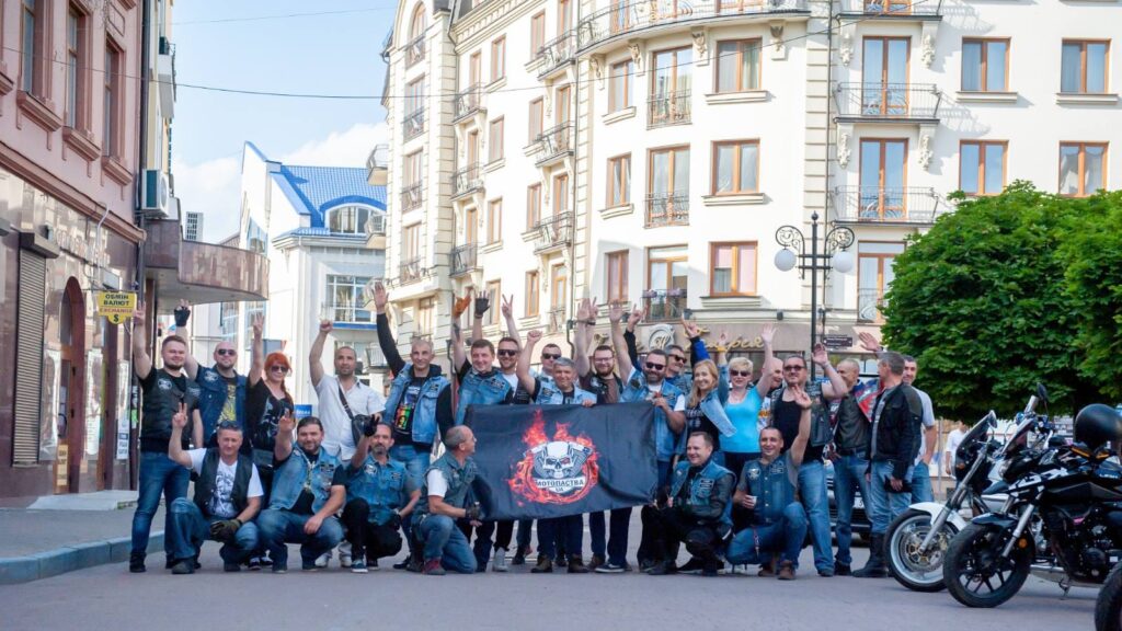 Група байкерів позує на вулиці біля будівлі.