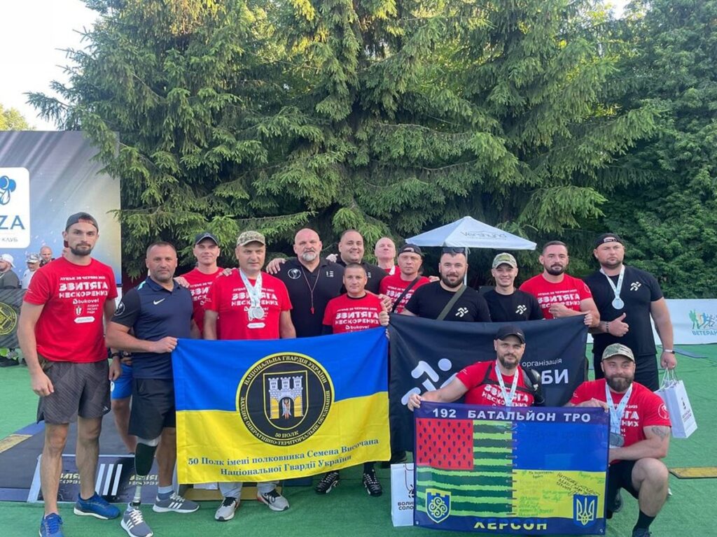 Група військових з прапорами на змаганнях в Україні.