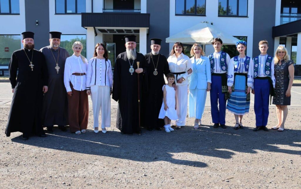Групове фото людей у традиційному одязі перед будівлею